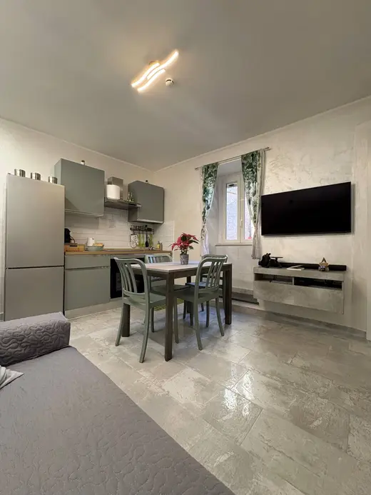 Soggiorno e cucina in un unico ambiente, con tavolo da pranzo e smart TV